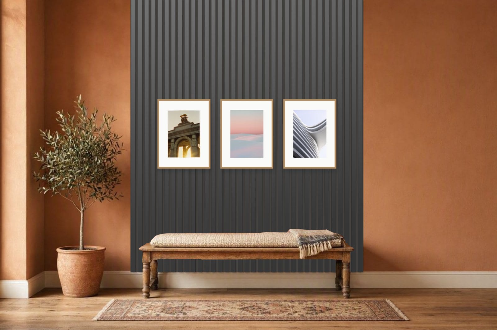 Black acoustic slats running down to the skirting behind a woven bench in a terracotta hallway, with three oak frames hung across the slats and an olive tree beside them