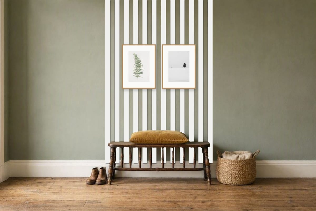 Two oak frames on white open battens running down to the skirting behind a wooden bench on a sage green hallway wall